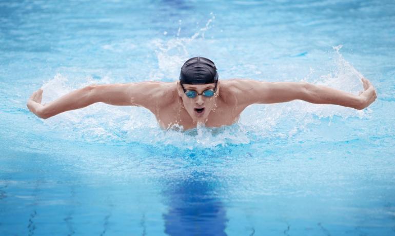 Nuotatore esegue stile farfalla in piscina.