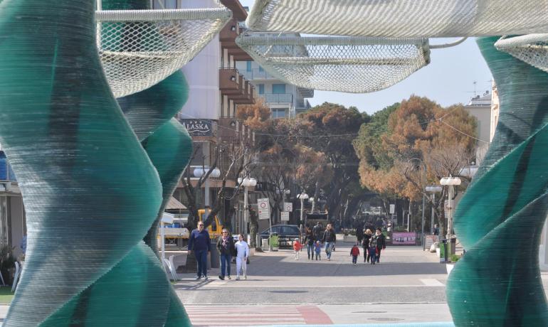 Strada pedonale con sculture e persone che passeggiano.