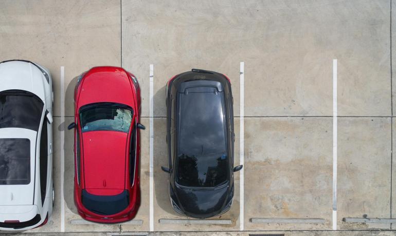 Tre auto parcheggiate, vista dall'alto, con due spazi vuoti a destra.