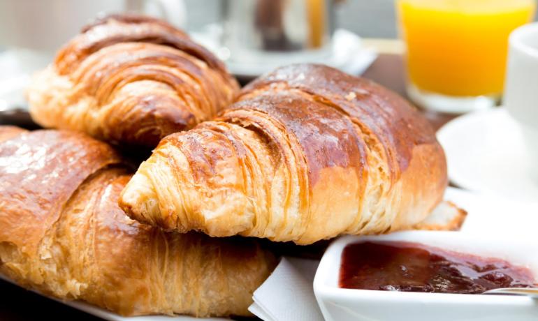 Croissant freschi con marmellata e succo d'arancia per colazione.