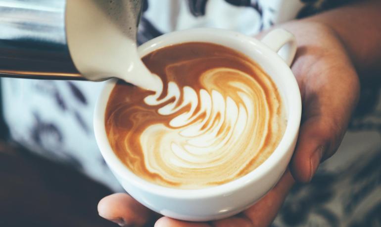 Cappuccino con latte art in tazza bianca.