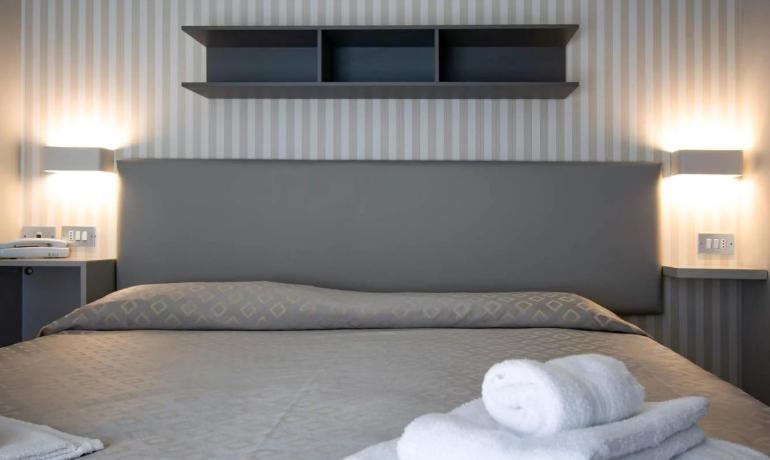 Camera moderna con letto e asciugamani bianchi.