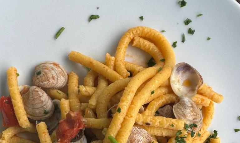 Pasta con vongole e pomodori, guarnita con prezzemolo.