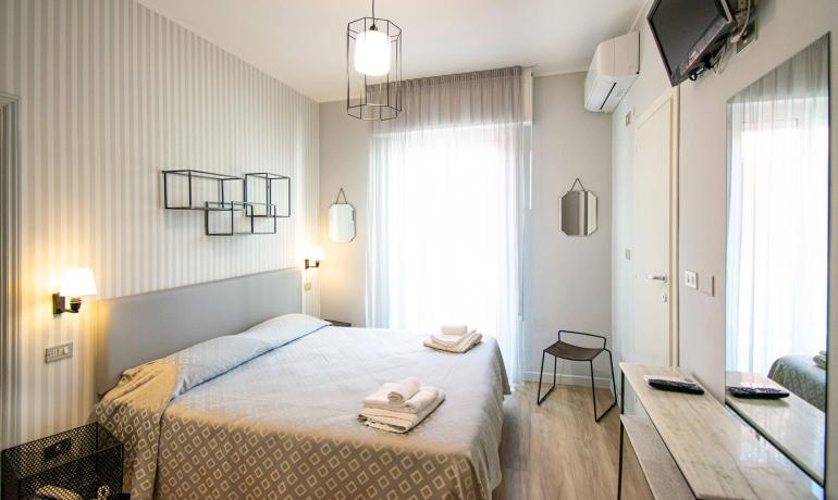 Camera moderna con letto matrimoniale e TV a parete.