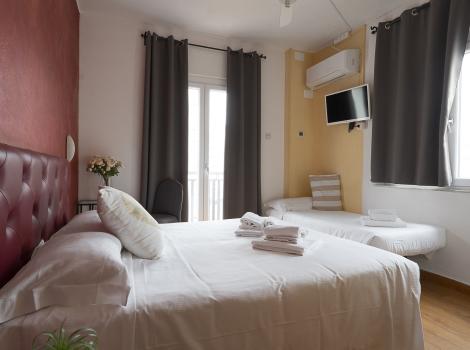 Camera da letto moderna con letto matrimoniale, TV, aria condizionata e lenzuola bianche.