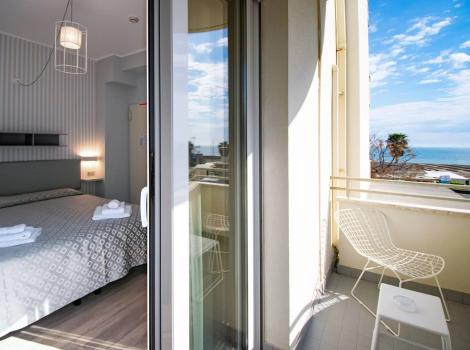 Camera moderna con balcone vista mare, arredamento elegante e accogliente.