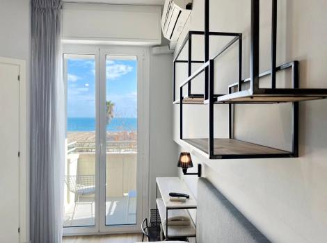 Camera moderna con vista mare, scaffali geometrici e arredi minimalisti.
