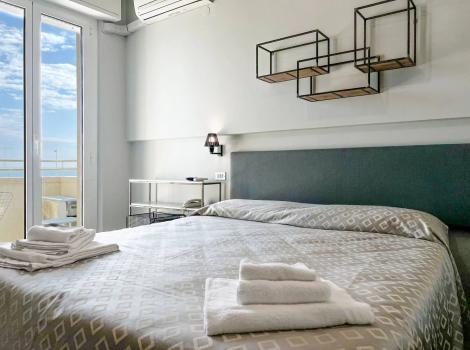 Camera moderna con letto matrimoniale, vista mare e decorazioni geometriche.